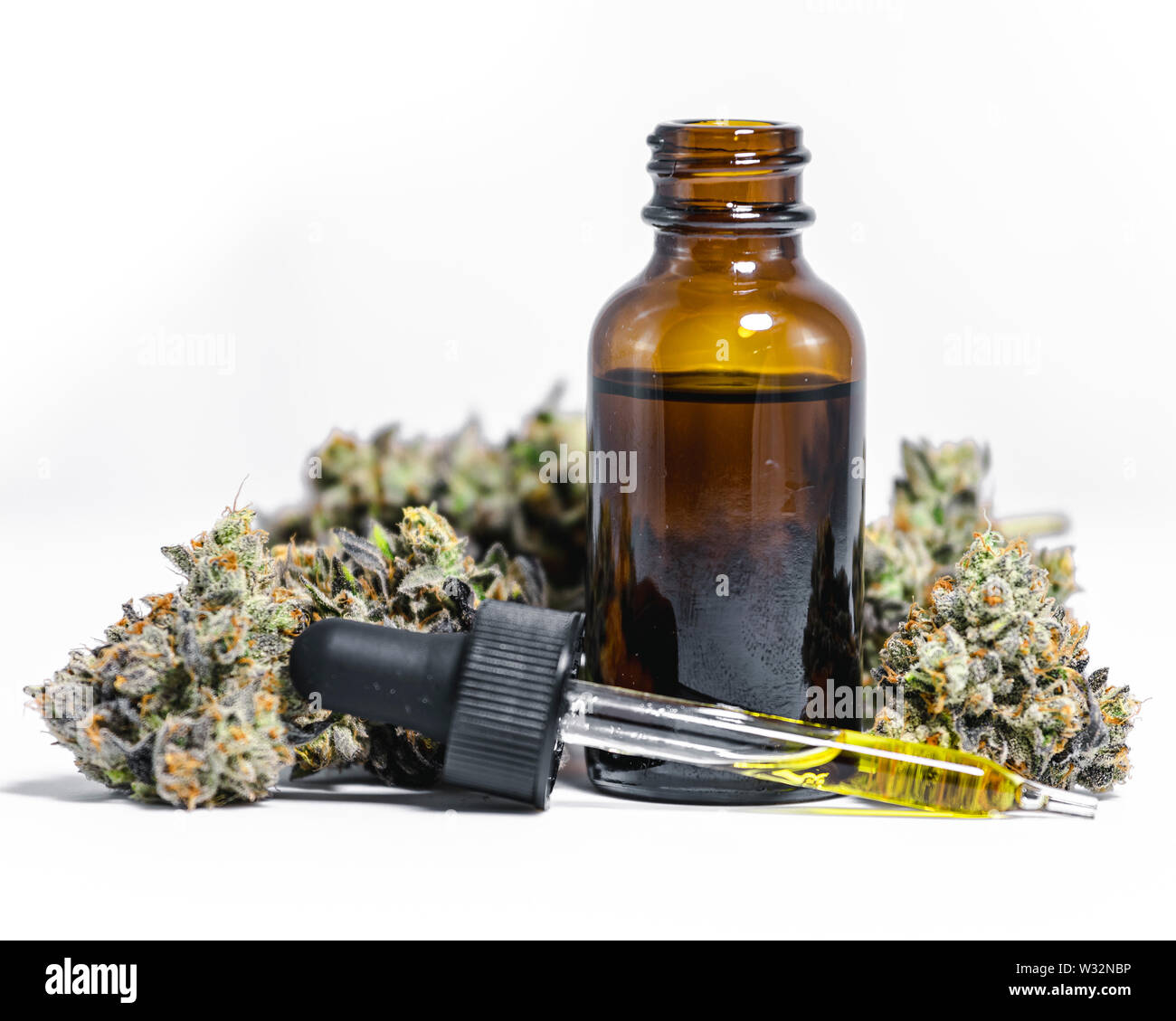 In der Nähe von hellen Display des natürlichen Cannabis Medizin in Glas Glas Fläschchen mit tropfenzähler der gelbe Flüssigkeit umgeben von Unkraut nugs Stockfoto
