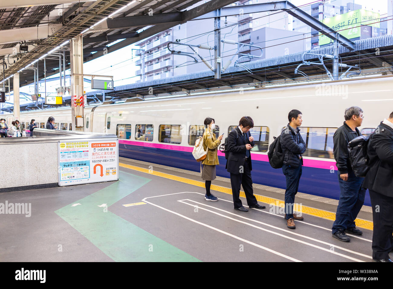 Tokio, Japan - April 4, 2019: Geschäftsleute, Unternehmer und Frau in Anzug mit Rucksack in der Schlange für anreisende Shinkansen, t Stockfoto