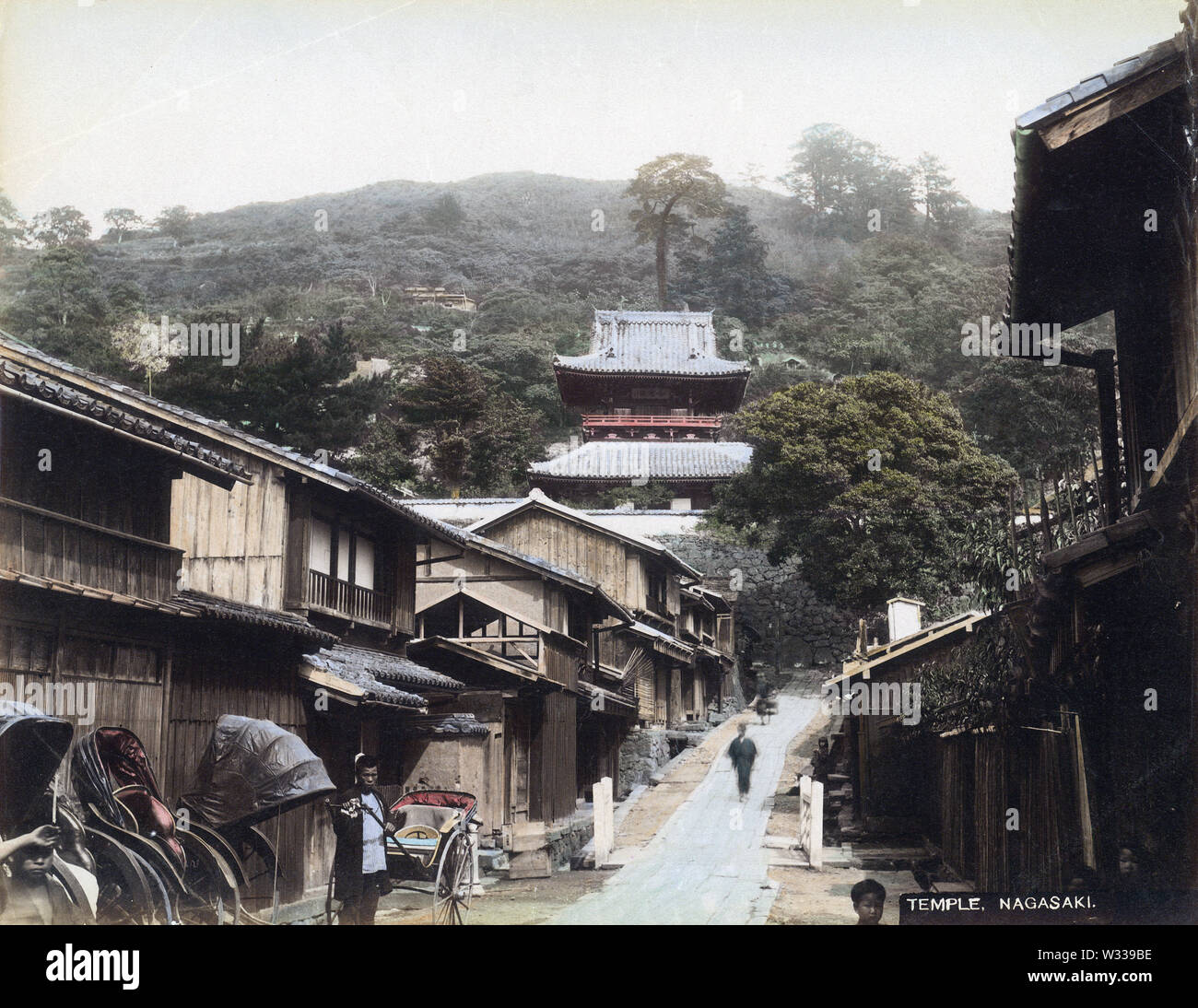 [1890s Japan - Buddhistische Tempel Bezirk in Nagasaki] - Rikschas bei Tera-machi in Nagasaki, als von Imakonya gesehen-machi und Nakakonya-machi (jetzt in Kojiya-machi). Die großen Struktur ist die Kaizando (Founder's Hall) von Kofukuji Tempel. Es brannte während des Zweiten Weltkriegs. 19 Vintage albumen Foto. Stockfoto
