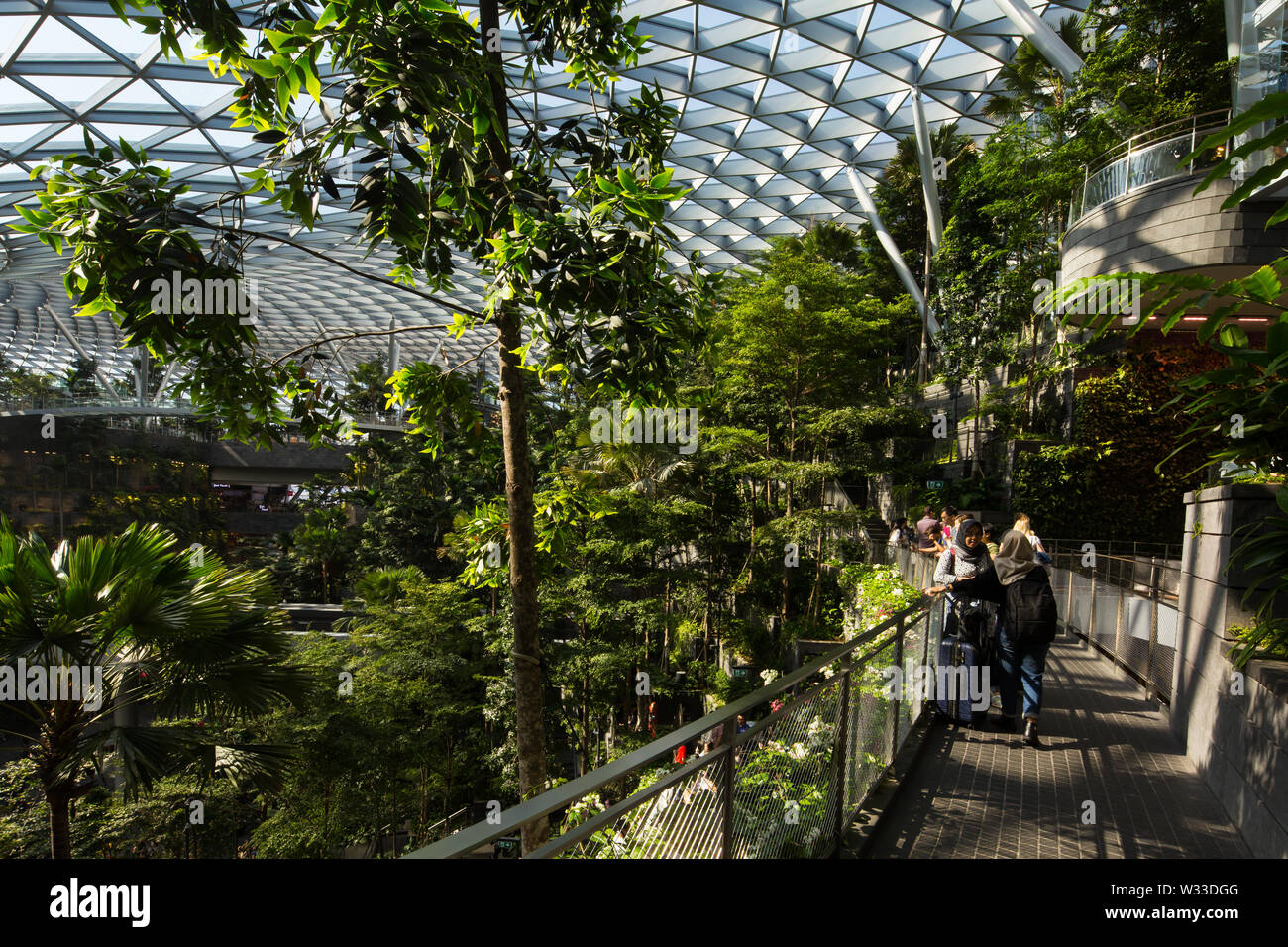 Touristen stehen entlang der Promenade genießen die üppigen Shiseido Forest Valley, Jewel Changi Airport, Singapur. Stockfoto