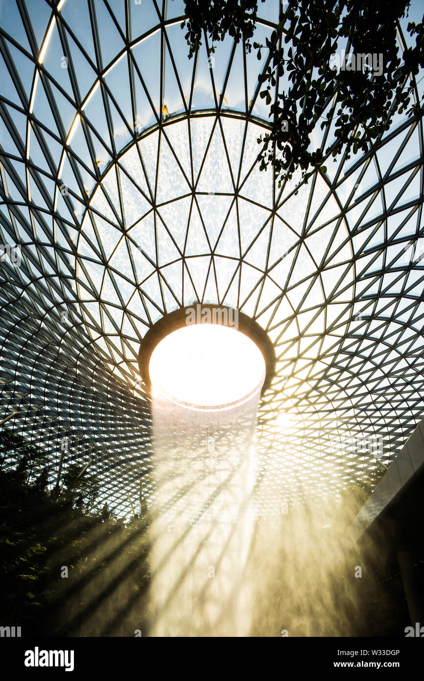 Vertikale Blick auf den Wasserfall und eine Dachterrasse mit schönen natürlichen Beleuchtung in Juwel Changi Airport kommen Stockfoto