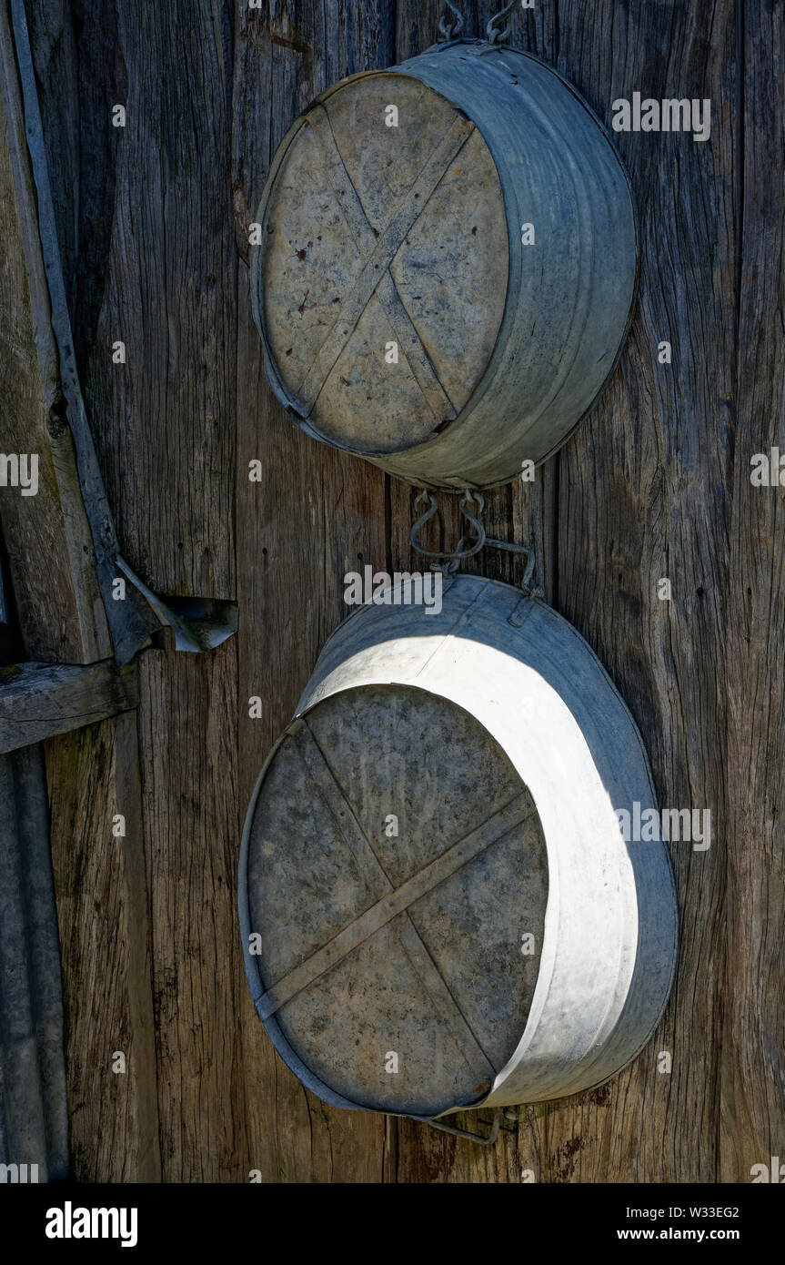 Zwei Zinn Bäder für Erwachsene und Kinder hängen auf einer Hütte an der Wand. Stockfoto