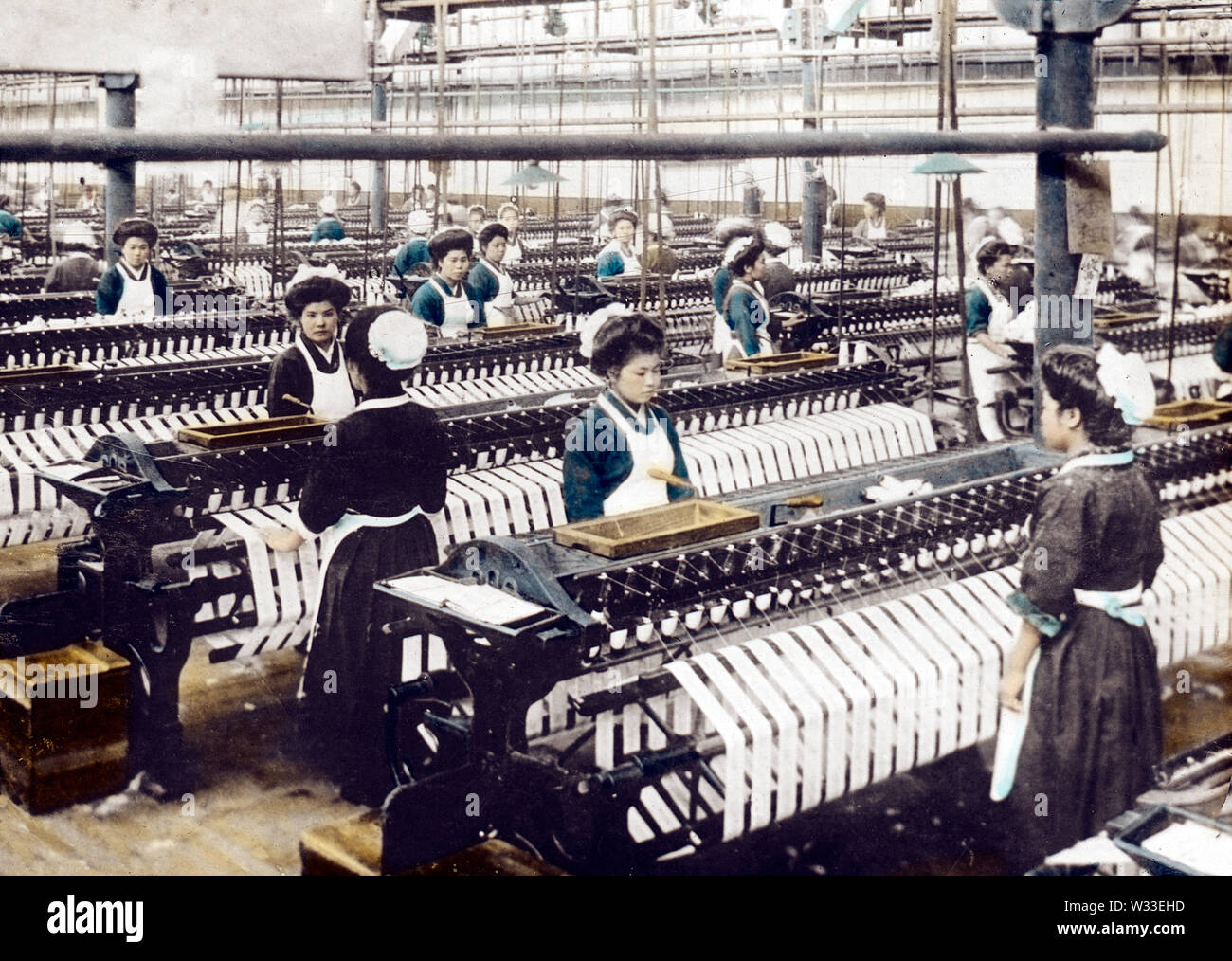 [1900s Japan - japanische Baumwolle spinnen Factory] - junge Frauen in Uniform im westlichen Stil an einem großen baumwollspinnerei Fabrik arbeiten. 20. Jahrhundert vintage Glas schieben. Stockfoto