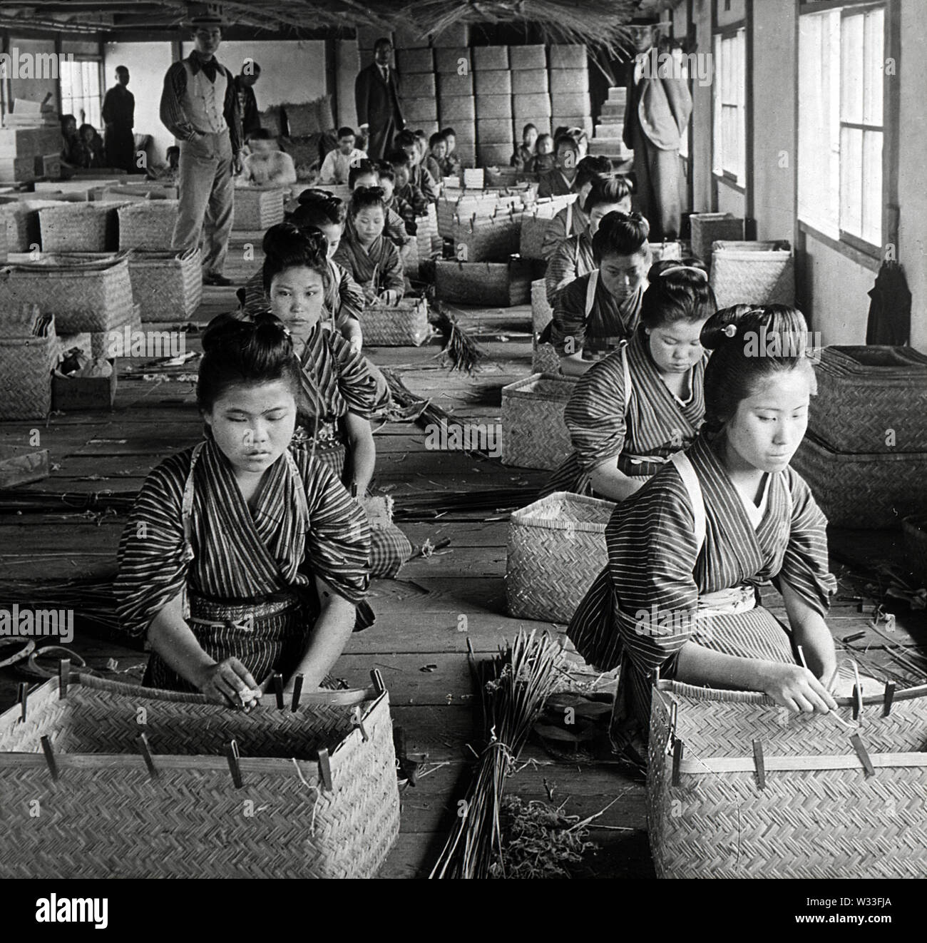 [1900s Japan - Japanische Frauen an der Arbeit an Bambus Warenkorb Factory] - Junge Mädchen und Frauen bei der Arbeit an einem Bambus Warenkorb Fabrik in 1904. 20. Jahrhundert vintage Glas schieben. Stockfoto