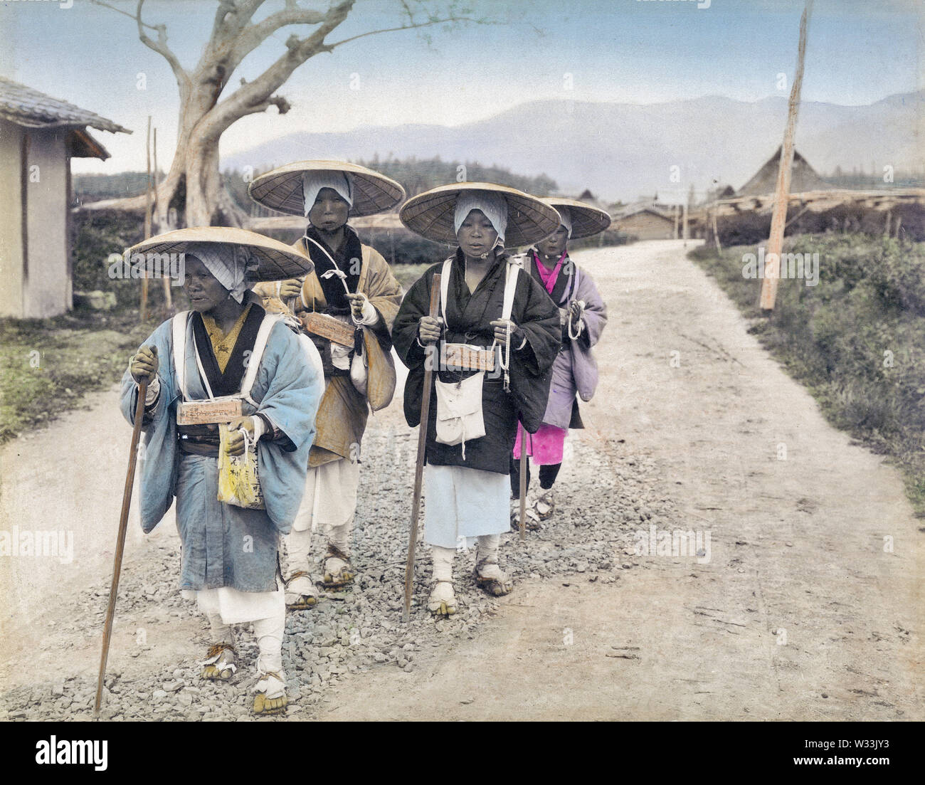 [1890s Japan - Japanische weibliche Pilger] - vier weibliche Pilger auf der Straße. Sie tragen sugegasa (segge - gewebt Hüte) und waraji (Stroh Sandalen), und Sie halten lange Stöcke. 19 Vintage albumen Foto. Stockfoto