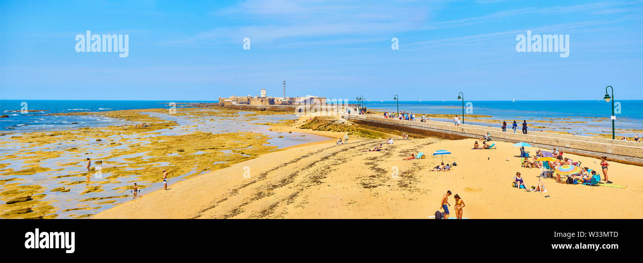 Die Menschen genießen Sie ein Sonnenbad in La Caleta Strand mit dem San Sebastian Castle, eine Festung in La Caleta Insel, im Hintergrund. Cadiz. Spanien Stockfoto