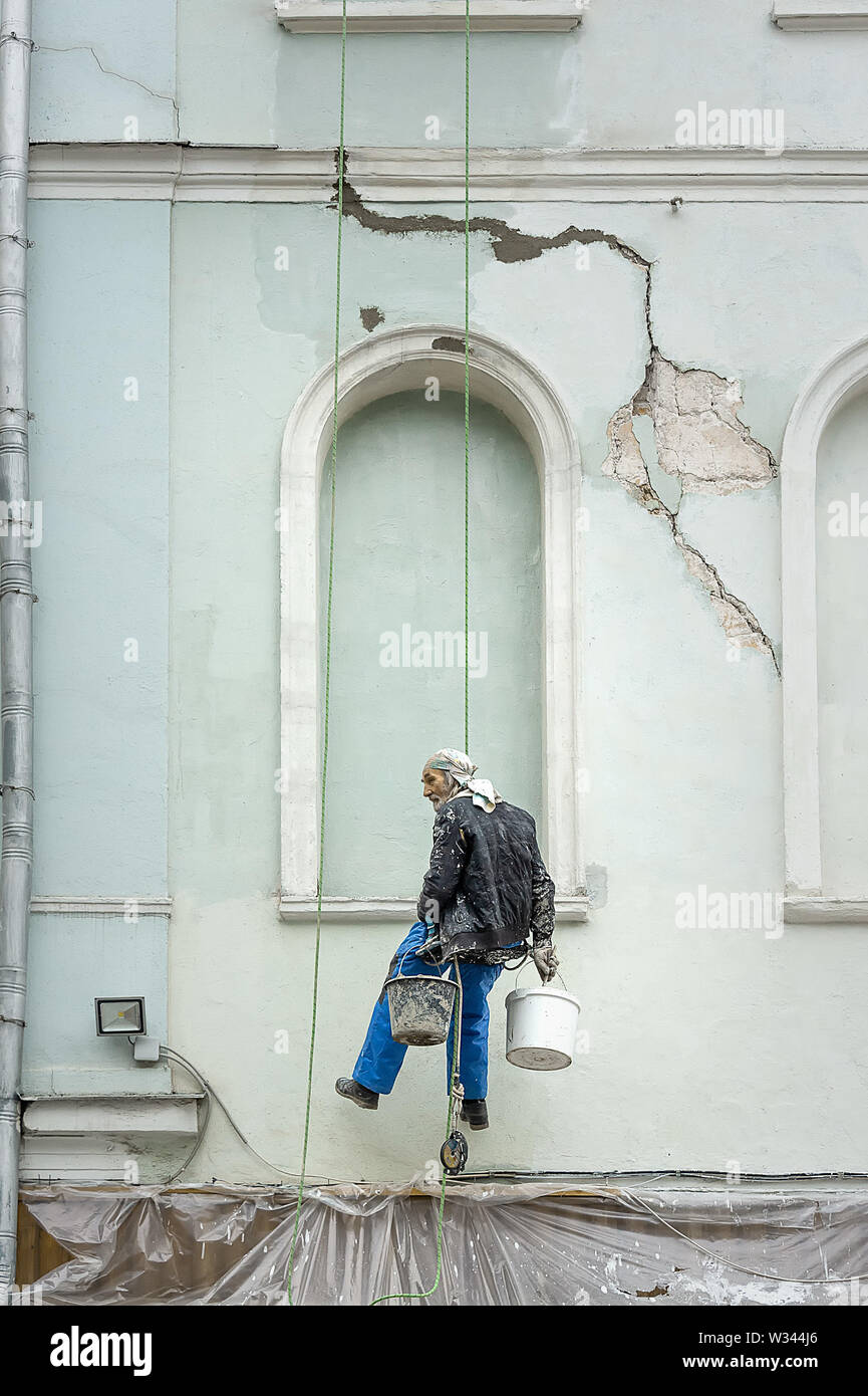 Moskau, Russland - Oktober 29, 2018: Alte Arbeitnehmer hängen an einem einzigen Seil Linie, die Vorbereitung der Wand eines alten Gebäudes zu lackieren. Stockfoto