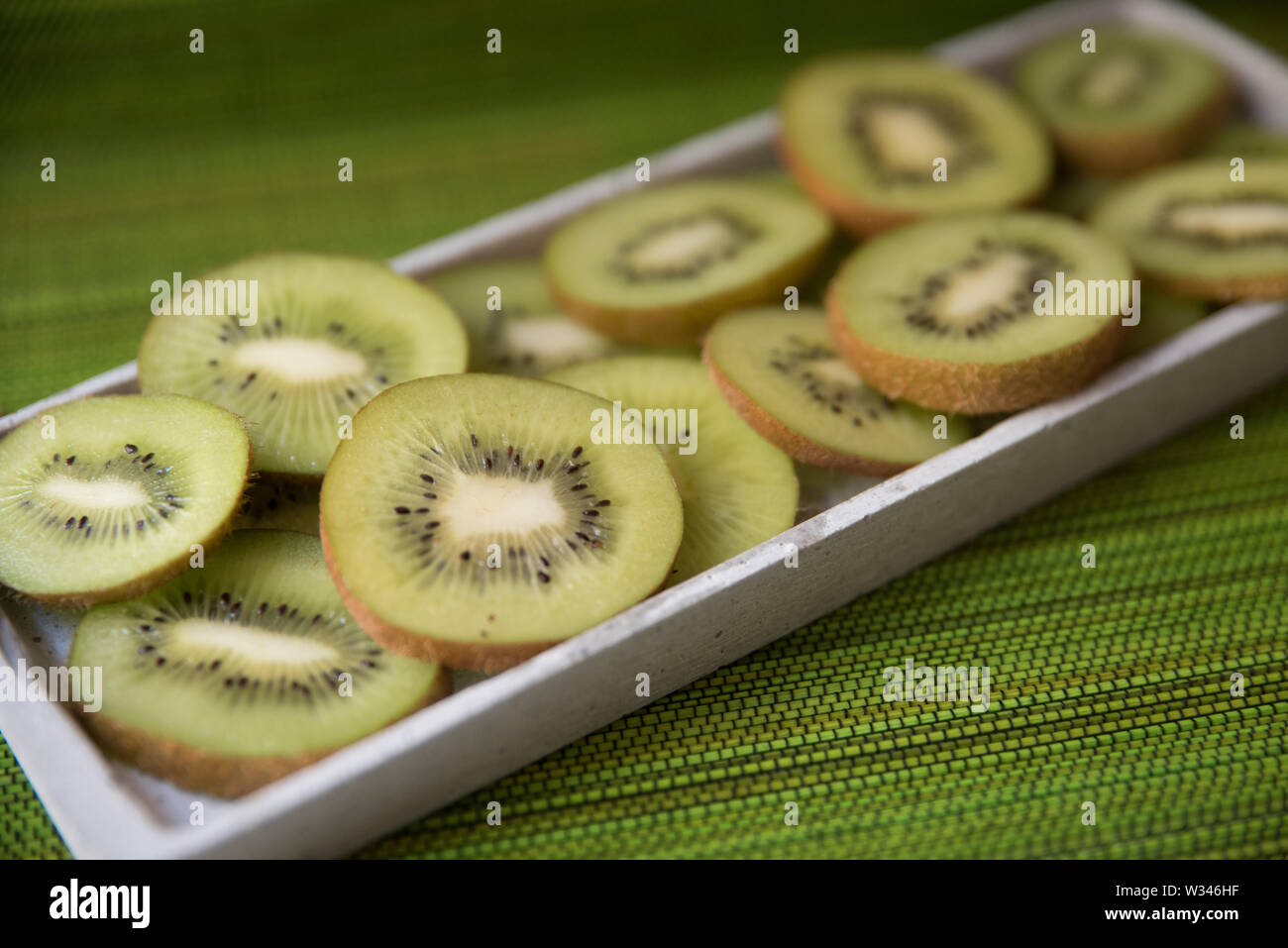 Frisches Grün Kiwis Kiwis mit brauner Haut auf einem Schneidebrett und grüner Hintergrund Stockfoto