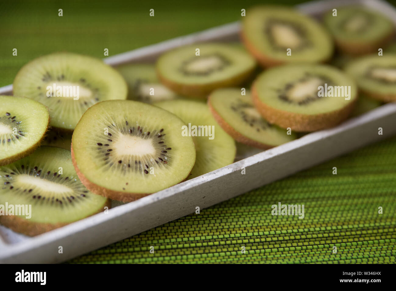 Frisches Grün Kiwis Kiwis mit brauner Haut auf einem Schneidebrett und grüner Hintergrund Stockfoto