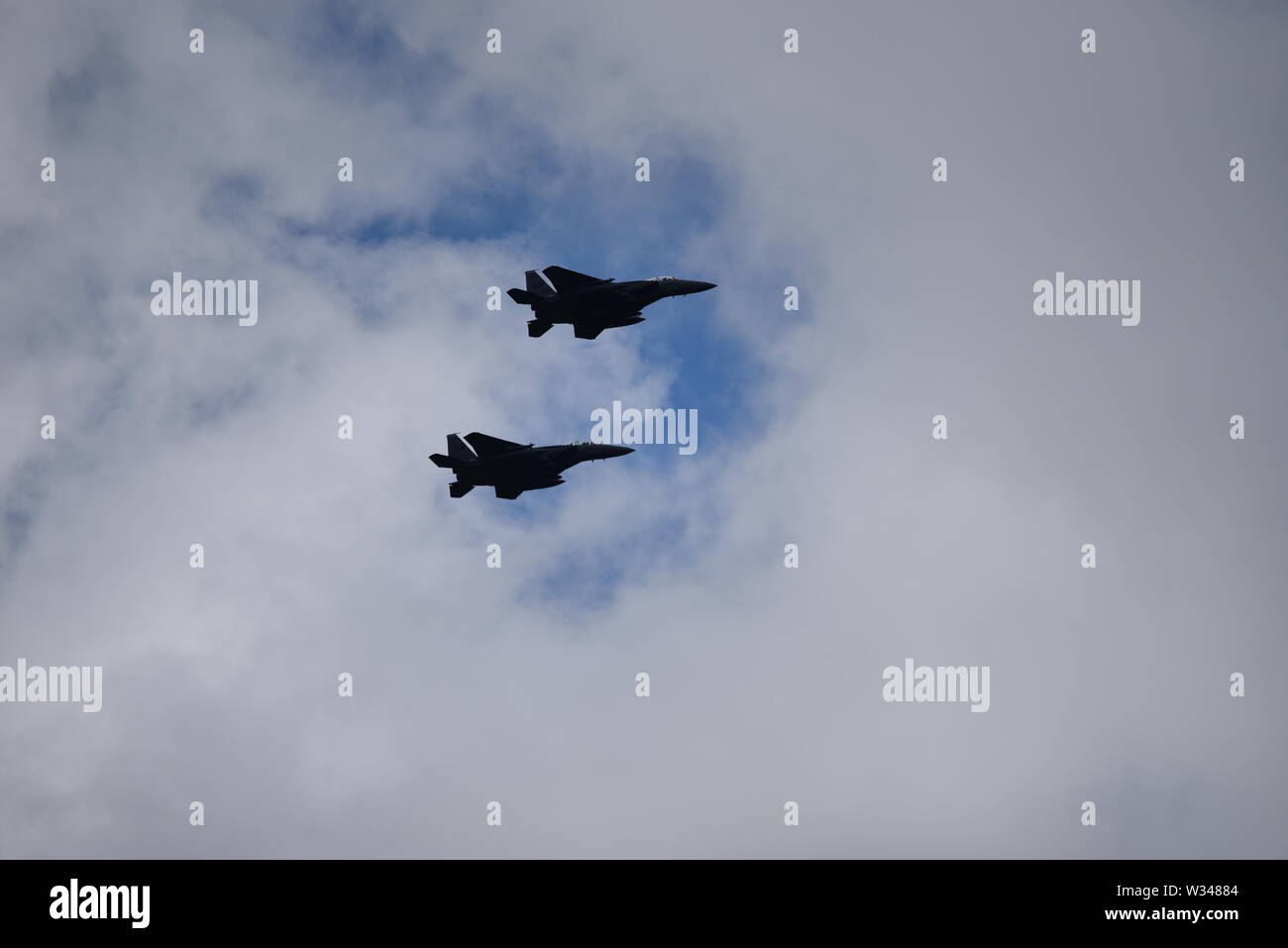 Paar F15 Eagle US-jet Kampfflugzeuge in der Ferne vor einem dunklen Grau bewölkter Himmel fliegen Stockfoto
