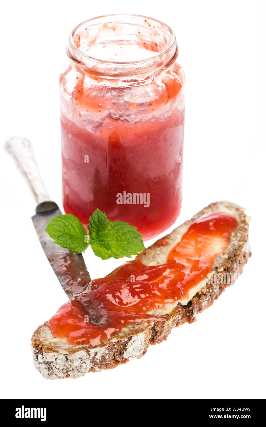 Erdbeermarmelade in Glas mit Brot, Messer und Minze Stockfoto