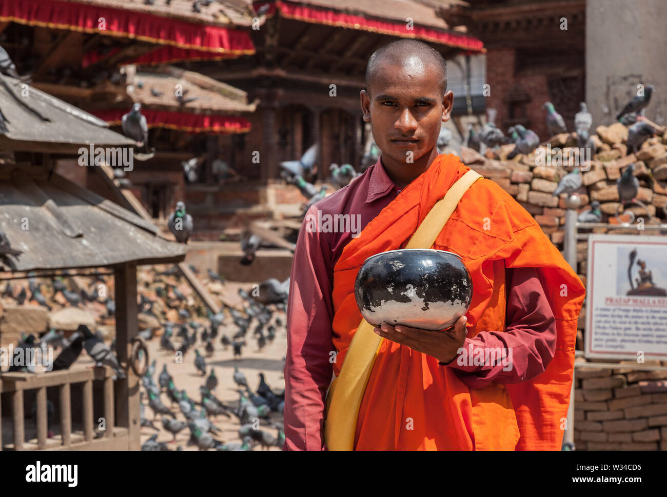 Buddhistischer Mönch in orangefarbene Gewänder sammeln Spenden für beschädigte Tempel in Kathmandu. Stockfoto