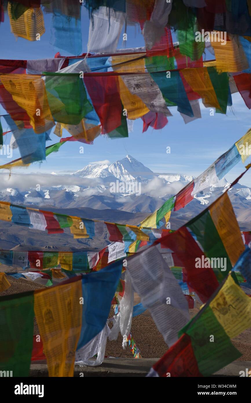 Mount Everest mit Gebetsfahnen im Vordergrund. Aus Tibet genommen, ist der atemberaubende Berg unter einem klaren blauen Himmel zu sehen. Stockfoto
