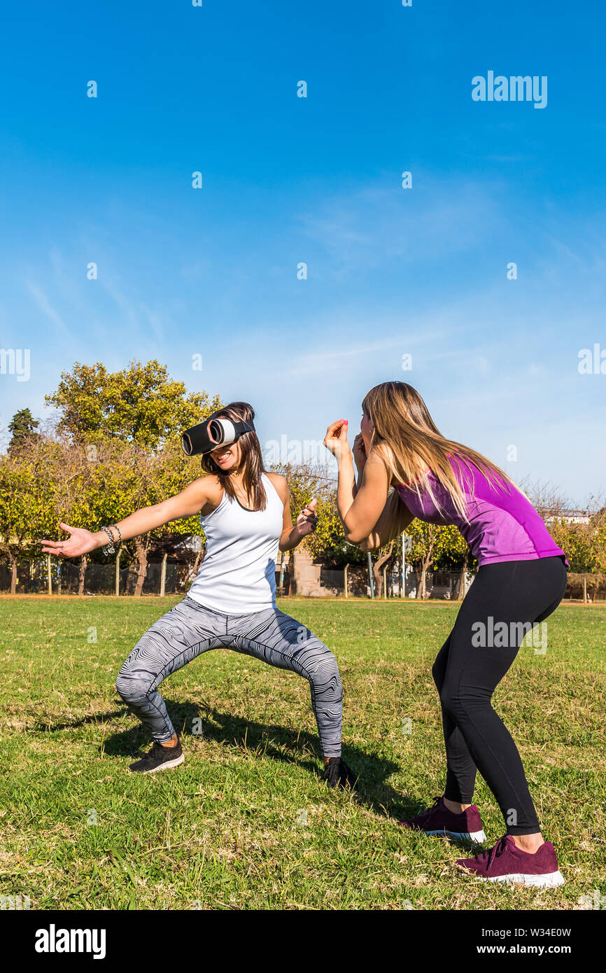 Zwei kaukasischen Frauen im Park, eine blonde und eine Brünette mit einer virtuellen Realität Maske Stockfoto