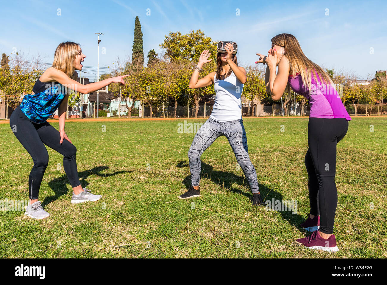 Drei kaukasischen Frauen im Park zwei Blondinen und eine Brünette mit virtueller Realität Maske Stockfoto