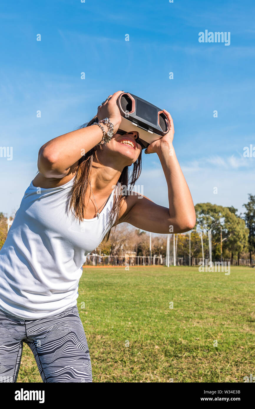 Kaukasische Frau im Park, brünett mit virtueller Realität Maske an einem sonnigen Tag mit blauen Himmel Stockfoto