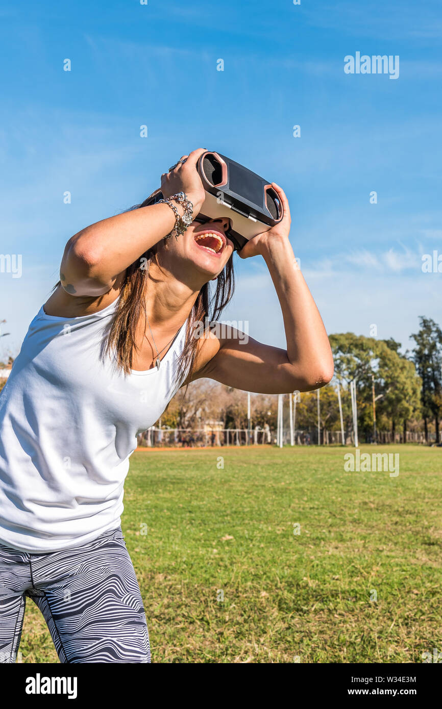 Kaukasische Frau im Park, brünett mit virtueller Realität Maske an einem sonnigen Tag mit blauen Himmel Stockfoto