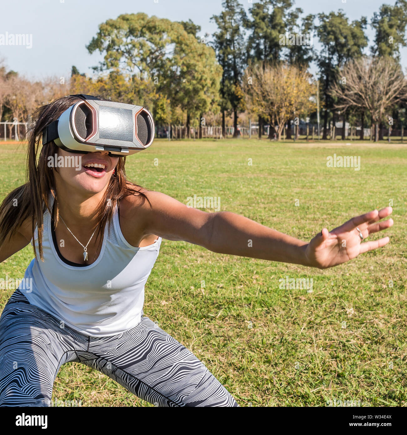 Kaukasische Frau im Park, brünett mit virtueller Realität Maske an einem sonnigen Tag mit blauen Himmel Stockfoto