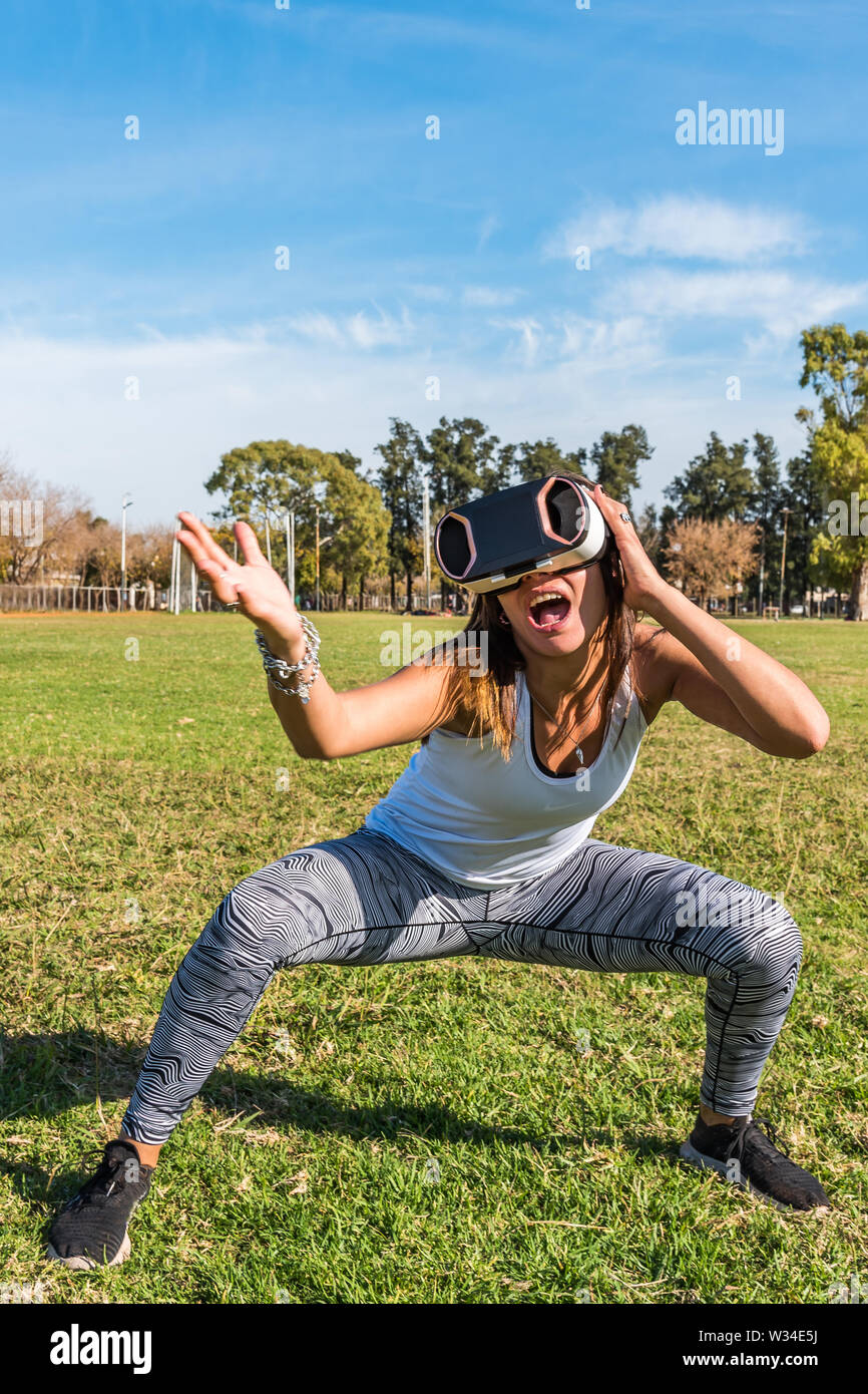 Kaukasische Frau im Park, brünett mit virtueller Realität Maske an einem sonnigen Tag mit blauen Himmel Stockfoto