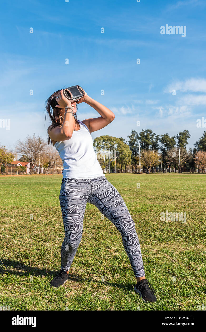 Kaukasische Frau im Park, brünett mit virtueller Realität Maske an einem sonnigen Tag mit blauen Himmel Stockfoto