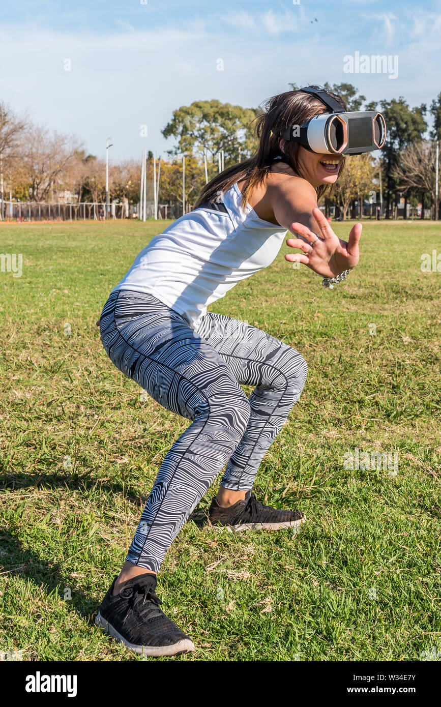 Kaukasische Frau im Park, brünett mit virtueller Realität Maske an einem sonnigen Tag mit blauen Himmel Stockfoto