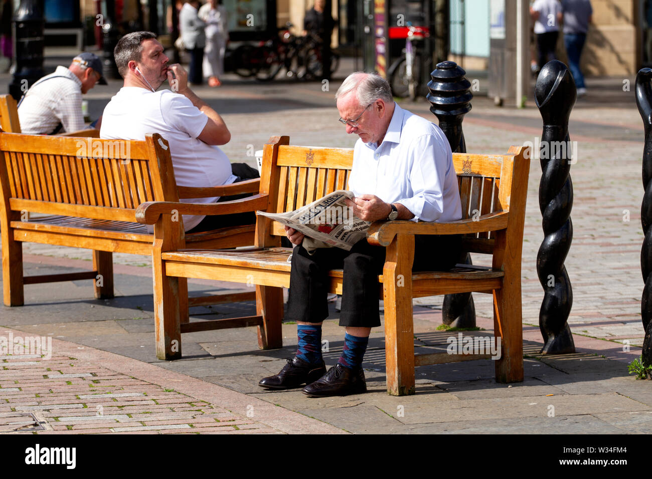 Tayside, Dundee, Schottland, Großbritannien. 12. Juli, 2019. UK Wetter: Ein alter Mann sitzt auf der Sommerterrasse sitzen Lesen der Kurier Zeitung in Dundee, Großbritannien Stockfoto