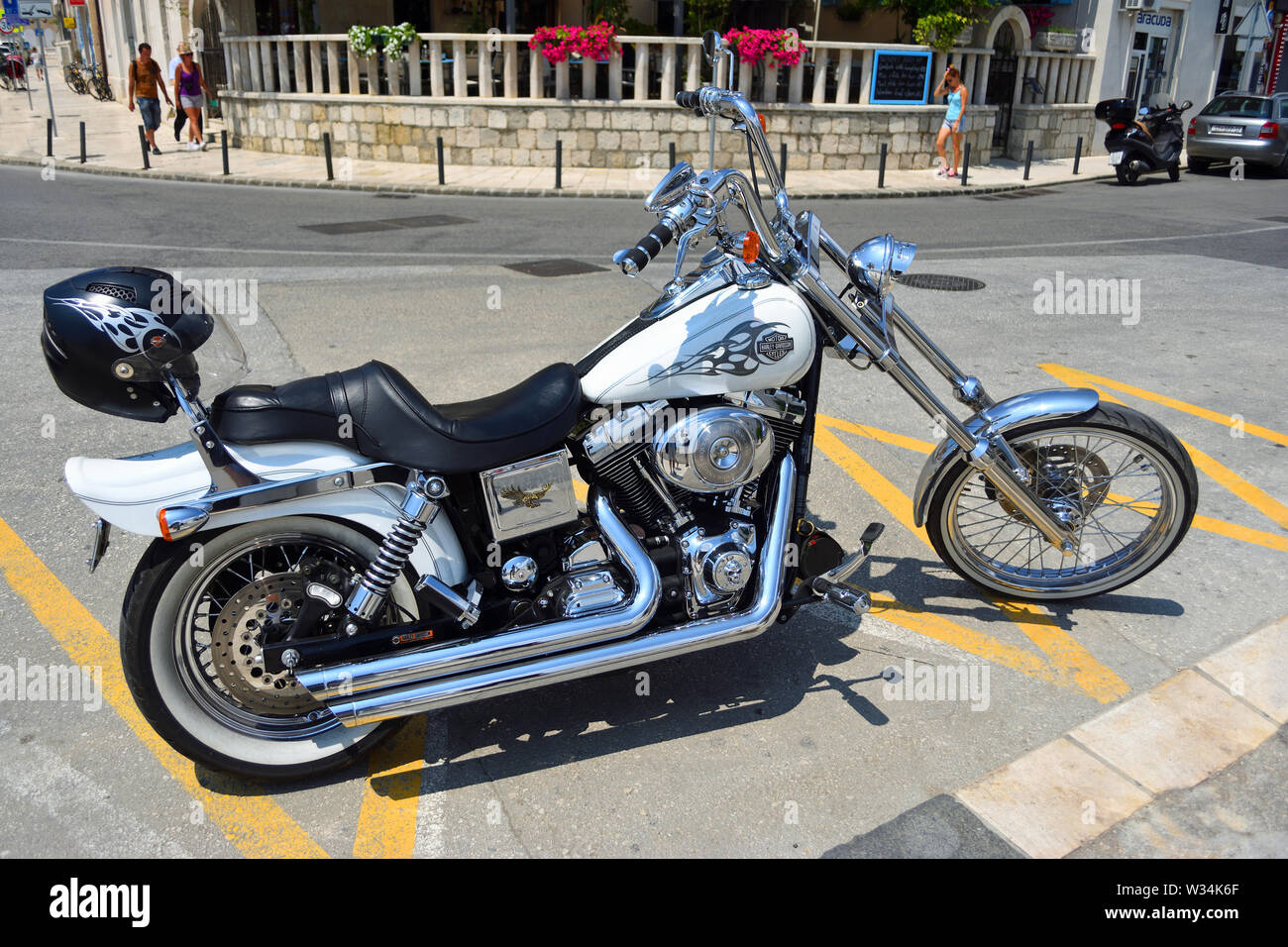 Harley Davidson Motorrad im Straßenverkehr mit Helm auf der Rückseite geparkt. Stockfoto