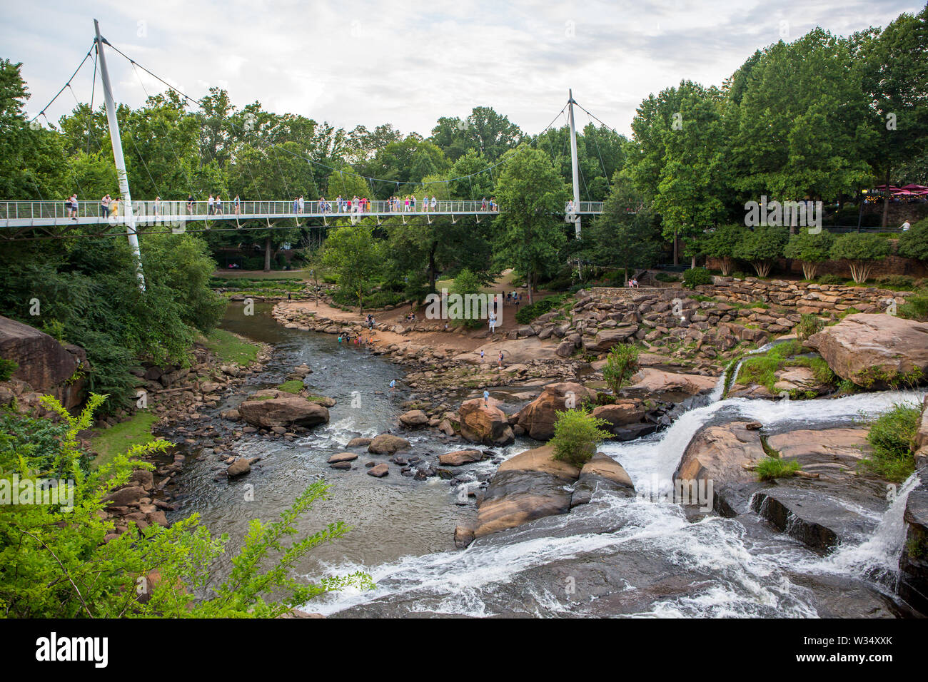 Besucher Falls Park auf Liberty Bridge mit Blick auf den Reedy River Wasserfälle in Greenville, South Carolina verweilen. Stockfoto