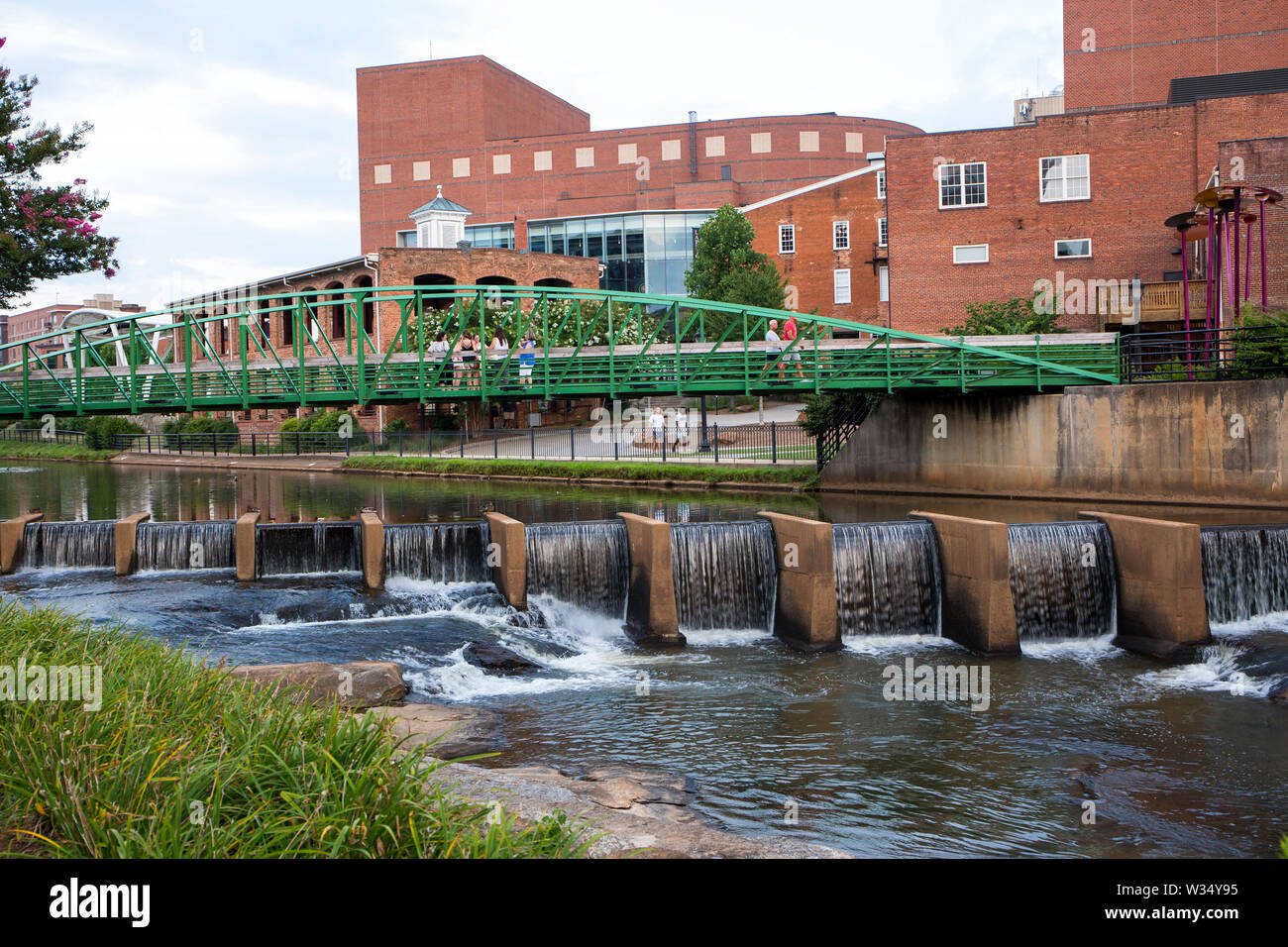 GREENVILLE, SC (USA) - Juli 5, 2019: Blick auf die Reedy River und Wasserfällen entlang des Flusses mit dem Eugenia Herzog Bridge im Hintergrund. Stockfoto