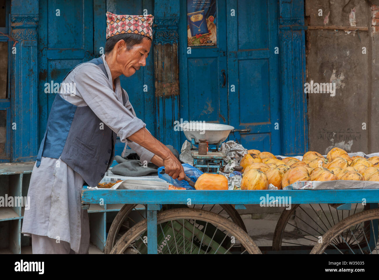 Man schneiden Mango auf seinem Essen Warenkorb in Kathmandu Stockfoto