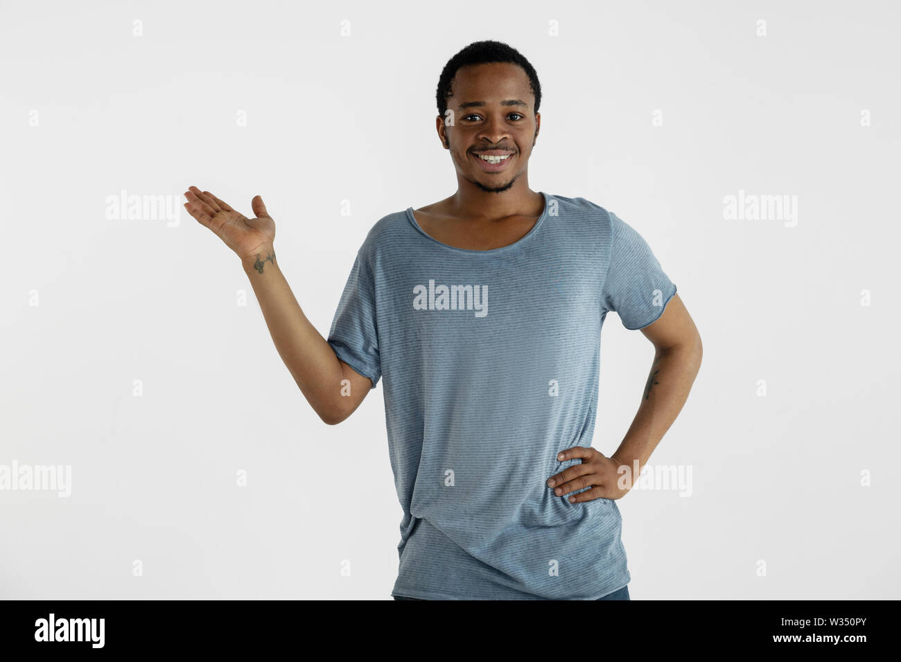 Schönen männlichen Portrait auf weißem Studiohintergrund. Junge emotionale Afrikanisch-amerikanische Mann im blauen Hemd. Mimik, menschlichen Emotionen, Ad-Konzept. Lächelnd, einladend, mit leeren Raum bar. Stockfoto