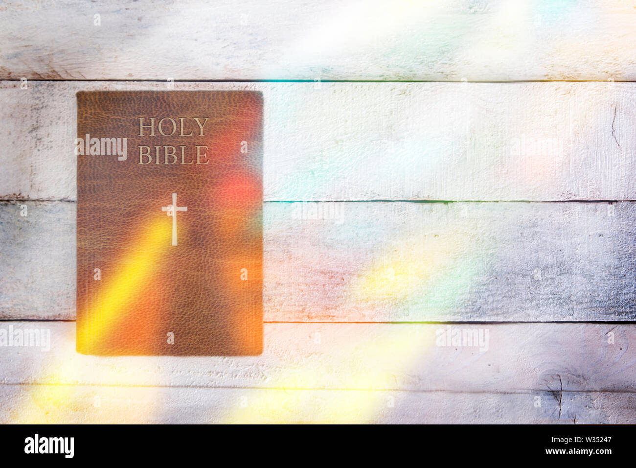 Heilige Bibel mit einigen Glasmalerei Reflexion auf einen hölzernen Tisch. Ansicht von oben und der leere Raum für Editor's Text. Stockfoto