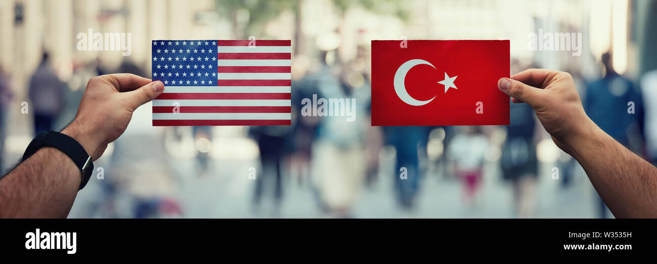 Zwei Hände, die verschiedene Flags, US vs Türkei auf Politik Arena überfüllten Straße Hintergrund. Diplomatie zukünftige Strategie, Beziehungen zwischen countri Stockfoto