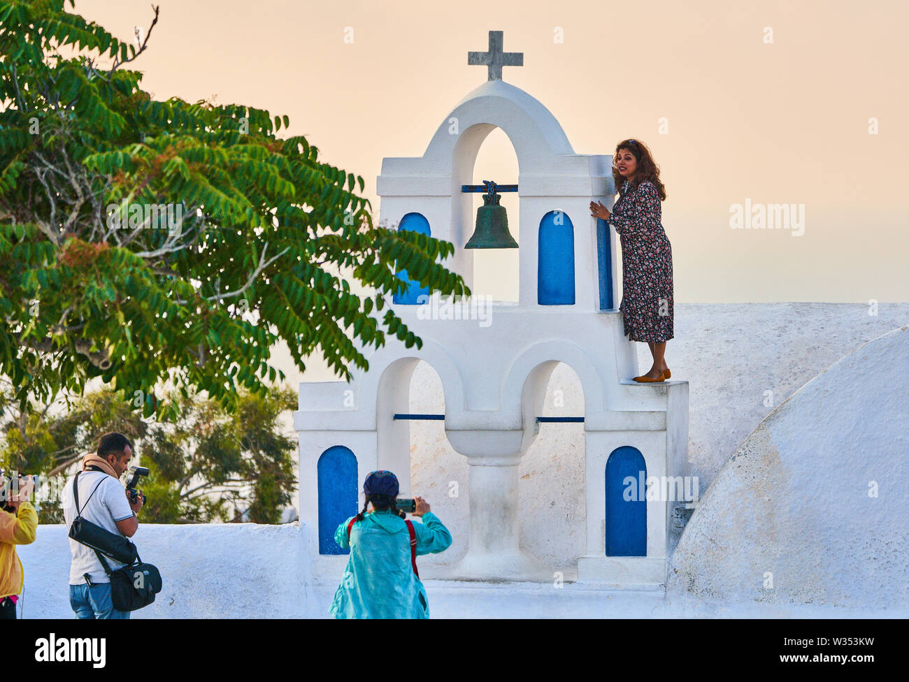 Touristen in Restaurants und auf Oia Castle warten auf den Sonnenuntergang mit Blick auf die Caldera und den berühmten Windmühle in Oia, Santorini, Griechenland, 04. Juni 2019. © Stockfoto