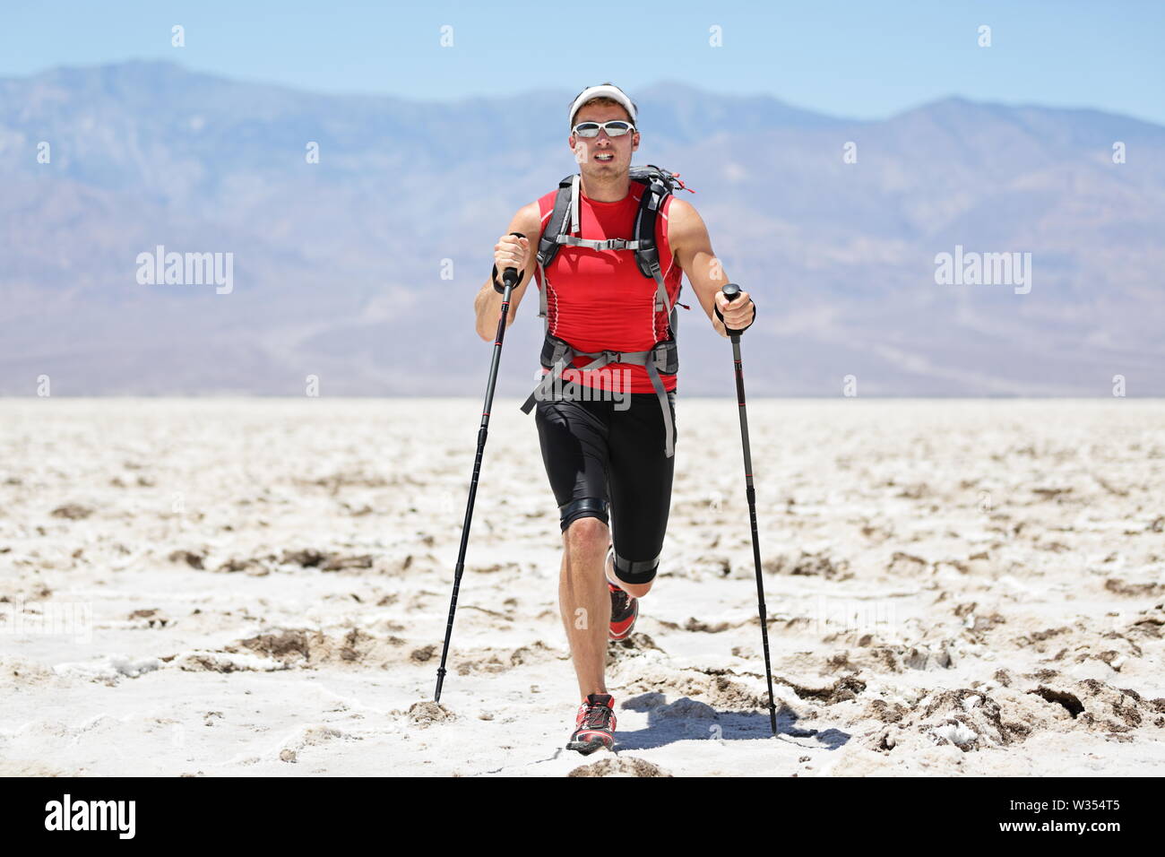 Ultra laufender Mann-Trail Runner in extreme race Training für Marathon. Passen männlichen Athleten mit Trekking Wanderstöcke im Death Valley, USA. Stockfoto