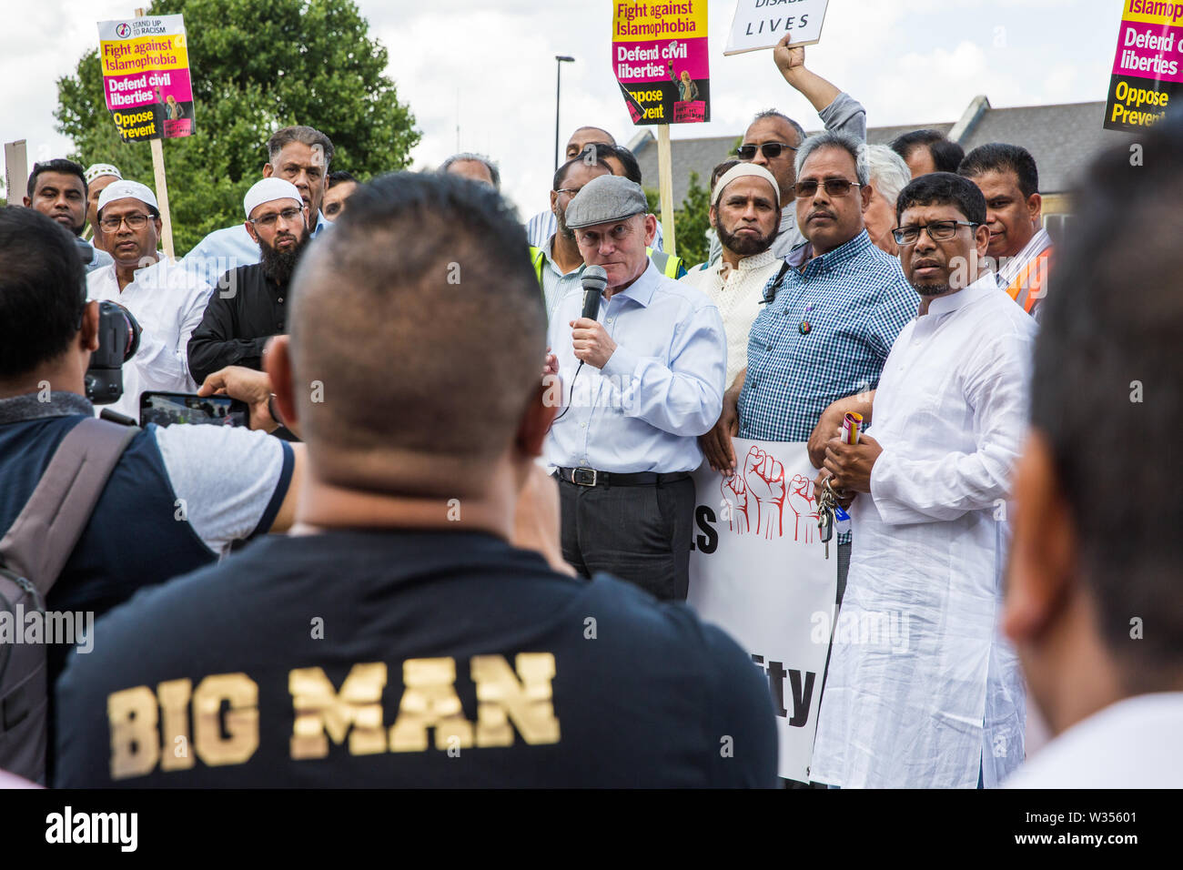 London, Großbritannien. 12. Juli, 2019. John Biggs, der Bürgermeister von Tower Hamlets, Adressen von einem Mitglied der lokalen Gemeinschaft (das Tragen der große Mann t-shirt), der ihn während eines Protestes in der Nähe von dem Ort, wo Youness Bentahar, im Alter von 38 kritisiert, gewaltsam von Metropolitan Police Officers am 10. Juli verhaftet wurde nach einer 5-stufigen Warnung. Der Vorfall, bei dem Herr Bentahar schien, in einem Anfall, hat seit der Metropolitan Police Central East Befehl professionelle Standards Unit bezeichnet worden, nachdem ein Video von der Verhaftung der viralen auf Social Media ging. Credit: Mark Kerrison/Alamy leben Nachrichten Stockfoto