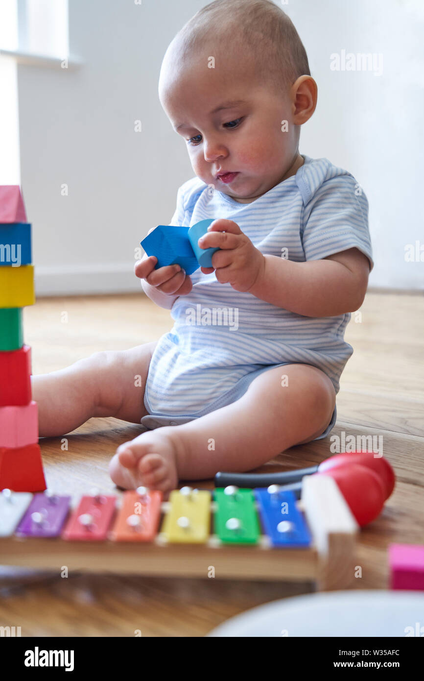 8 Monate alten Baby Boy Lernen durch Spielen mit farbigen Holzklötze zu Hause Stockfoto