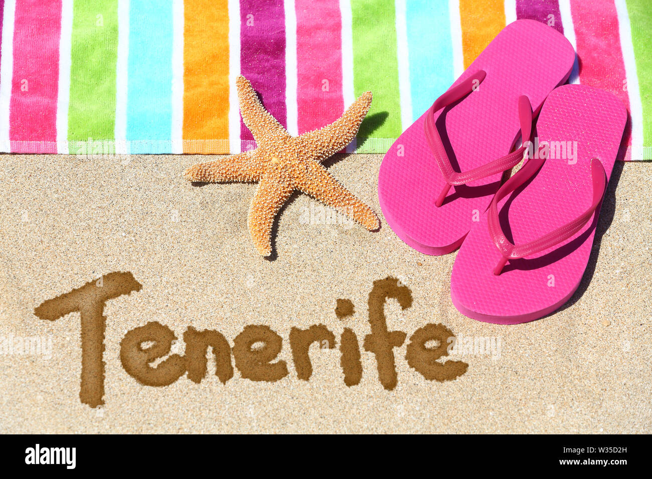 Teneriffa Strand reisen Hintergrund Konzept. Teneriffa in Sand geschrieben mit Wasser neben Strandtuch, Sommer Sandalen und Seesterne. Sommer und Sonne urlaub Urlaub auf den Kanarischen Inseln, Spanien. Stockfoto