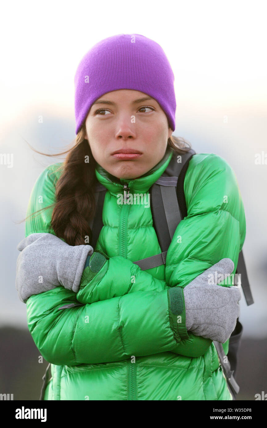 Einfrieren Frau Gefühl kalt draußen zu warm Schütteln und Zittern, tragen, Hut und Handschuhen außerhalb Wandern auf Wanderung halten. Stockfoto