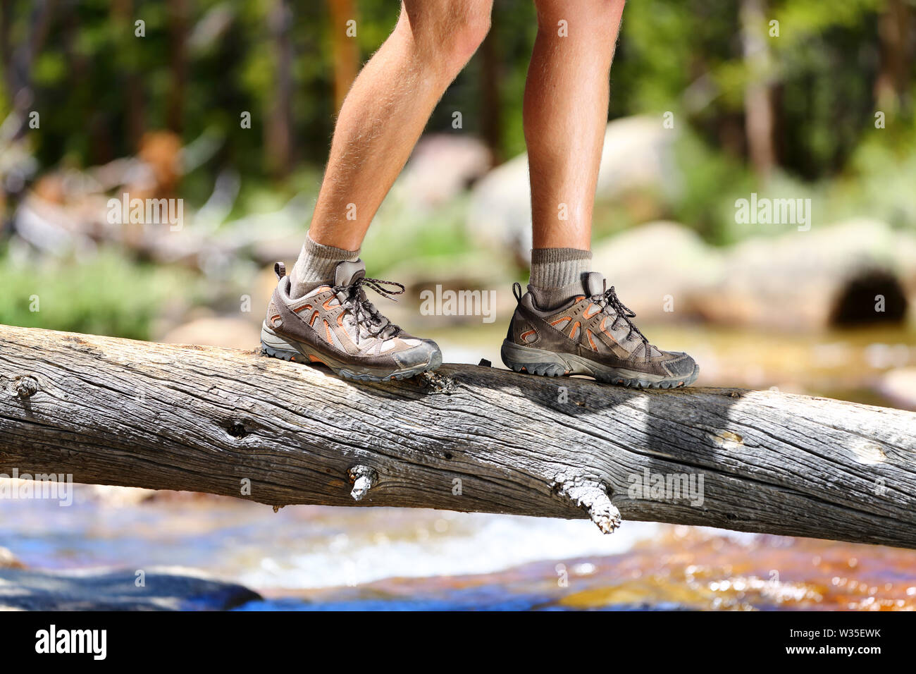 Wandern mann Fluß zu Fuß in das Gleichgewicht gefallenen Baumstamm in der Natur Landschaft. Nahaufnahme der männlichen Wanderer Trekking Schuhe draussen im Wald auf Baum. Balance challenge Konzept. Stockfoto