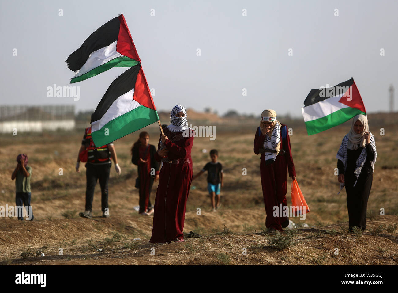 (190712) - GAZA, 12. Juli 2019 (Xinhua) - palästinensische Frauen halten Fahnen bei Auseinandersetzungen mit israelischen Truppen auf der Gaza-Israel Grenze, östlich von Gaza-stadt, 12. Juli 2019. Mindestens 40 Palästinenser am Freitag bei Auseinandersetzungen mit israelischen Soldaten im Osten Gazastreifen verletzt wurden, in der Nähe der Grenze zu Israel, die Ärzte sagten. (Str/Xinhua) Stockfoto