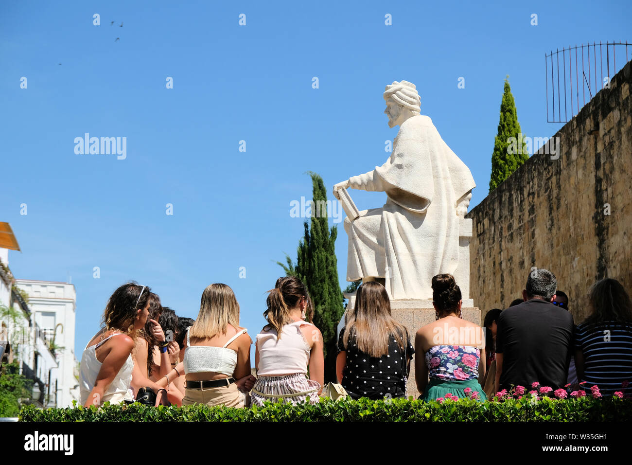 Statue des mittelalterlichen Philosophen Averroes in Cordoba, Spanien, mit modernen Studenten an der Sockel der Statue als ob in der Klasse hören auf ihn. Stockfoto