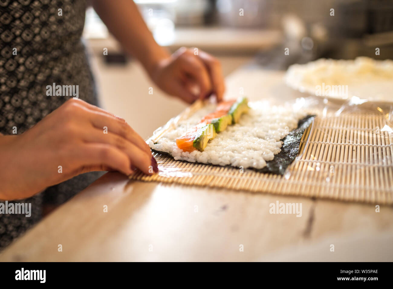 Eine Frau vorbereiten Hausgemachte Sushi und Brötchen. Die Sushi. Der Prozess der Vorbereitung Rolling Sushi. Stockfoto