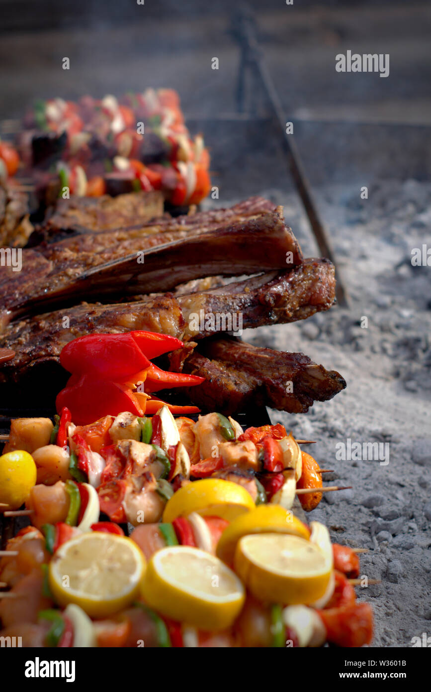 Ein typischer Argentinischer Grill. Ein großes Stück Fleisch und Gemüse Spieße auf dem Grill. Stockfoto