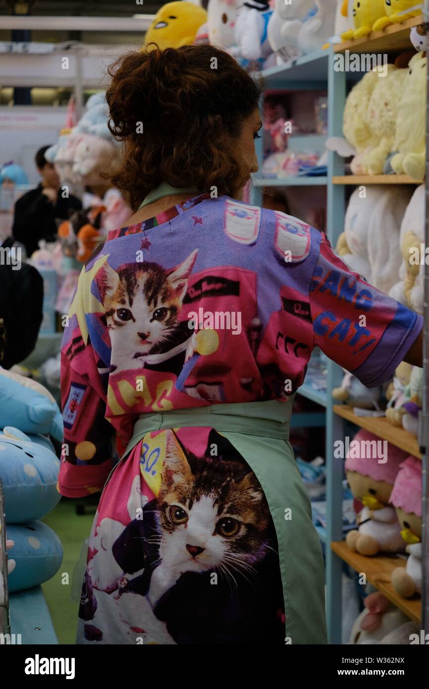 Frau in Kitsch Kätzchen Drucken Robe räumt Regale bei Store in Hyper Japan Stockfoto