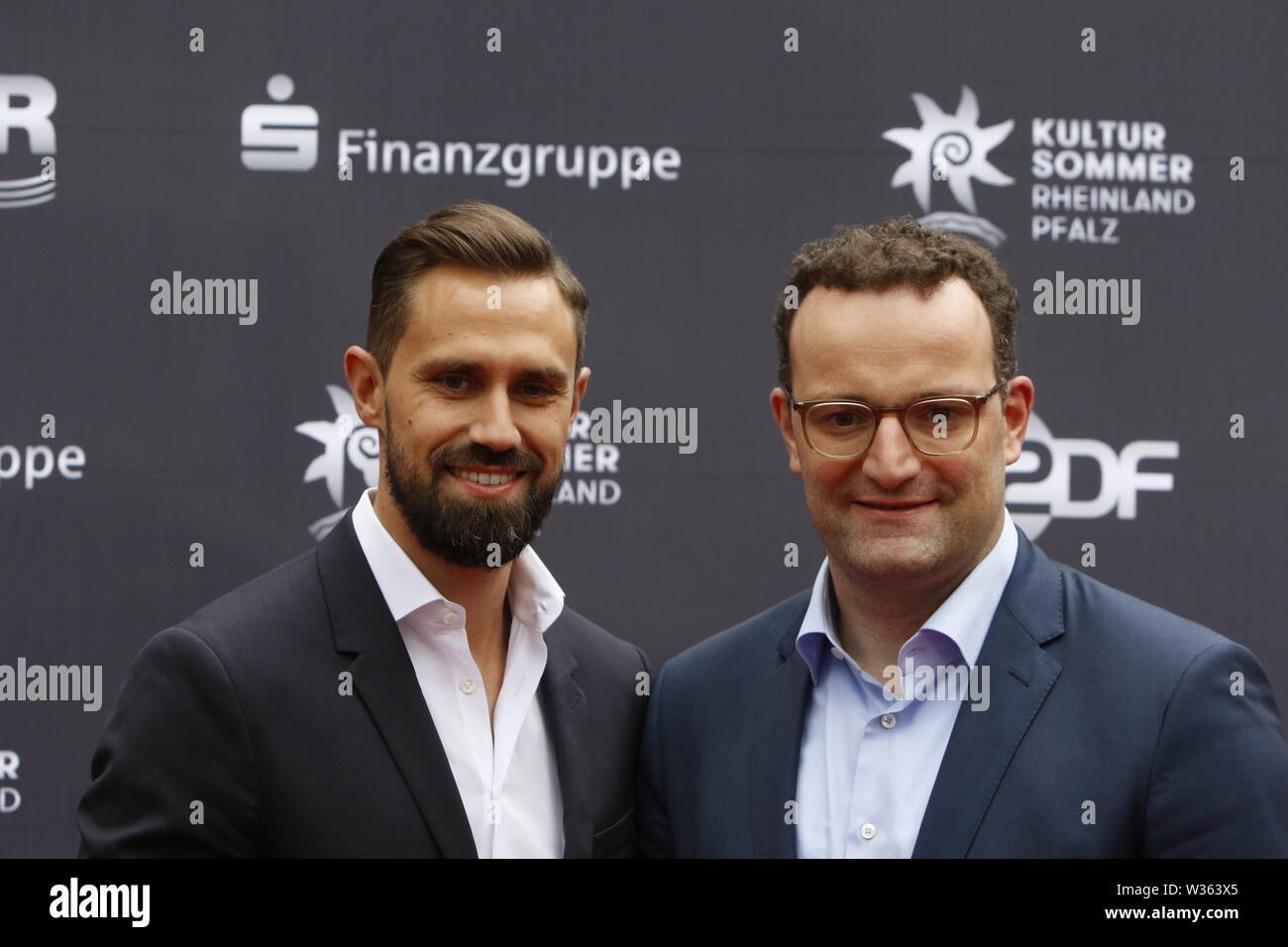 Worms, Deutschland. 12. Juli 2019. Der Bundesminister für Gesundheit Jens Spahn (rechts) und sein Ehemann Daniel Funke (links) bei der Premiere der "Nibelungen-Festspiele' ankommen. Schauspieler, Politiker und andere VIPs nahmen an der Eröffnung der Nibelungen-festspiele Nibelungen-Festspiele (2019) in Worms. Das Spiel in der 18. Saison des Festivals ist "Uberwaltigung' (Überwinden) zum Thema Thomas Melle, und von Lilja Rupprecht geleitet. Es erzählt von der ursprünglichen Lied der Nibelungen, beginnend am Ende und versucht, die Geschichte zu einem besseren, weniger tödlichen Versuch umschreiben. Stockfoto