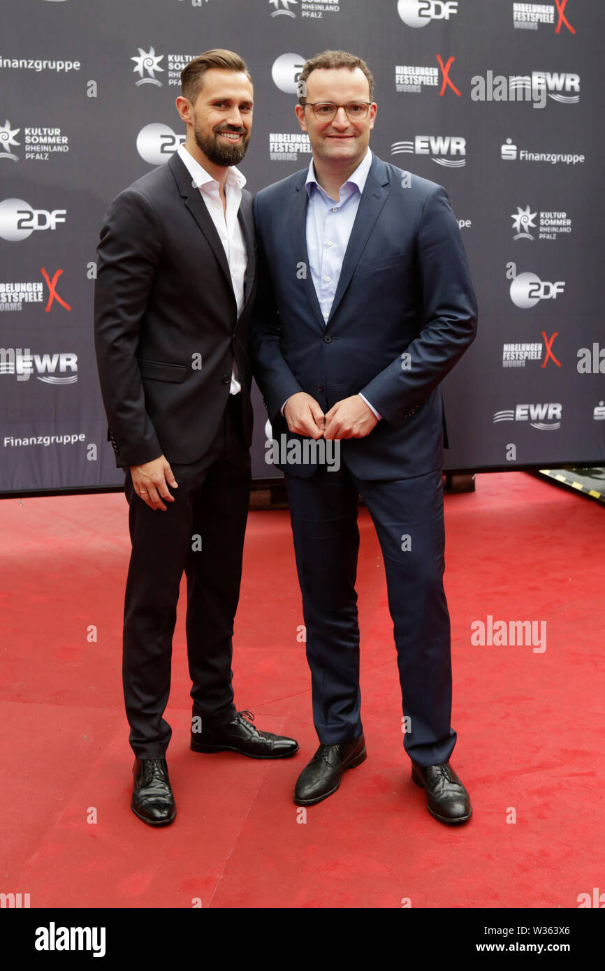 Worms, Deutschland. 12. Juli 2019. Der Bundesminister für Gesundheit Jens Spahn (rechts) und sein Ehemann Daniel Funke (links) bei der Premiere der "Nibelungen-Festspiele' ankommen. Schauspieler, Politiker und andere VIPs nahmen an der Eröffnung der Nibelungen-festspiele Nibelungen-Festspiele (2019) in Worms. Das Spiel in der 18. Saison des Festivals ist "Uberwaltigung' (Überwinden) zum Thema Thomas Melle, und von Lilja Rupprecht geleitet. Es erzählt von der ursprünglichen Lied der Nibelungen, beginnend am Ende und versucht, die Geschichte zu einem besseren, weniger tödlichen Versuch umschreiben. Stockfoto