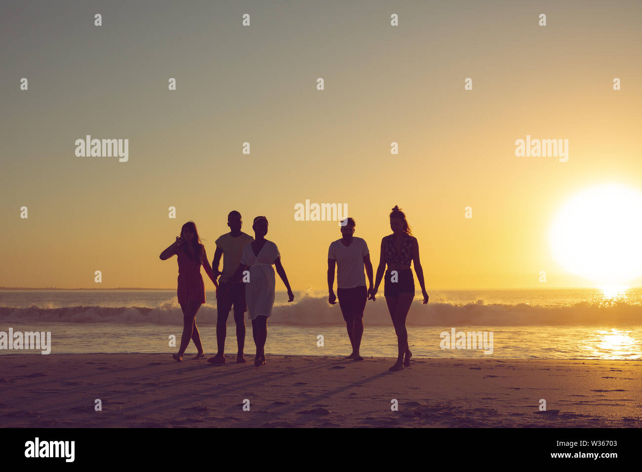 Freunde zusammen zu Fuß auf den Strand bei Sonnenuntergang Stockfoto