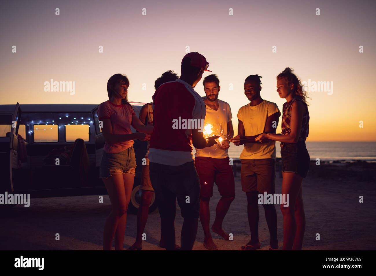 Freunde Beleuchtung Wunderkerzen in der Nähe von Kameramann bei Sonnenuntergang Stockfoto