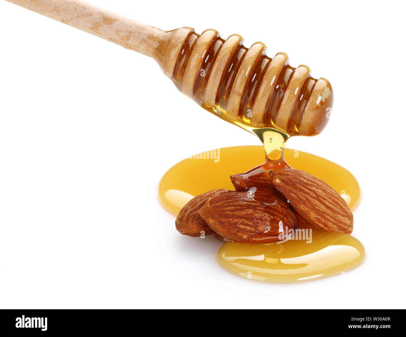 Honig tropft vom Pendelarm, auf Mandeln auf weißem Hintergrund Stockfoto